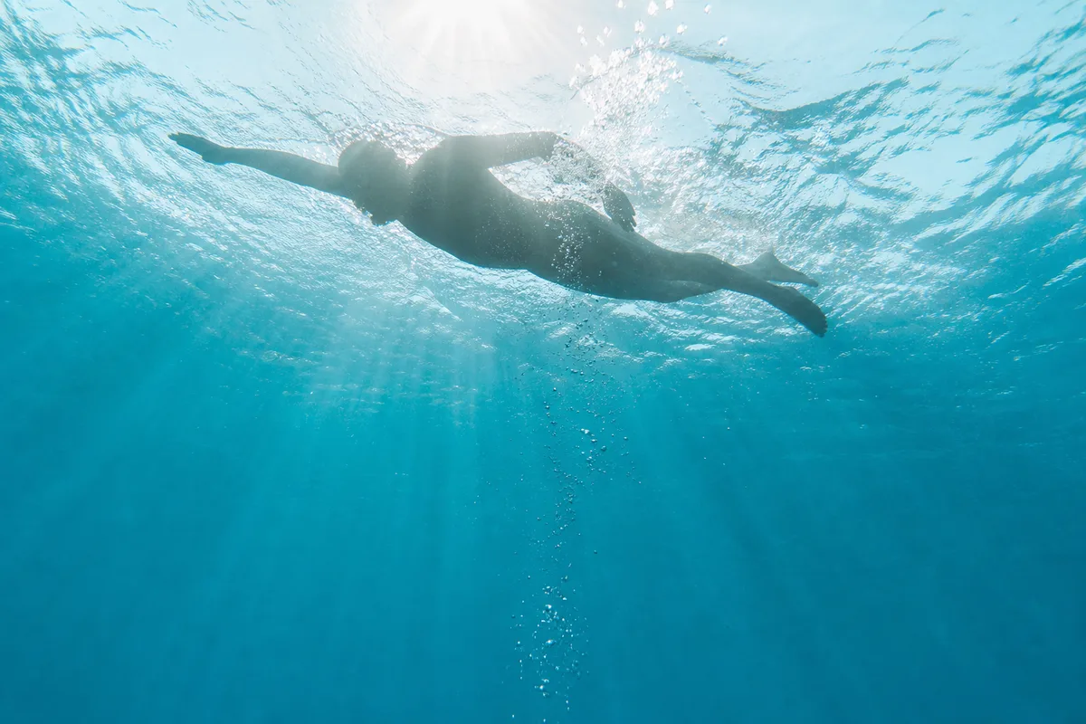 Vue subaquatique d&rsquo;un nageur expirant un chapelet de bulles sous l&rsquo;eau dans un bassin bleu
